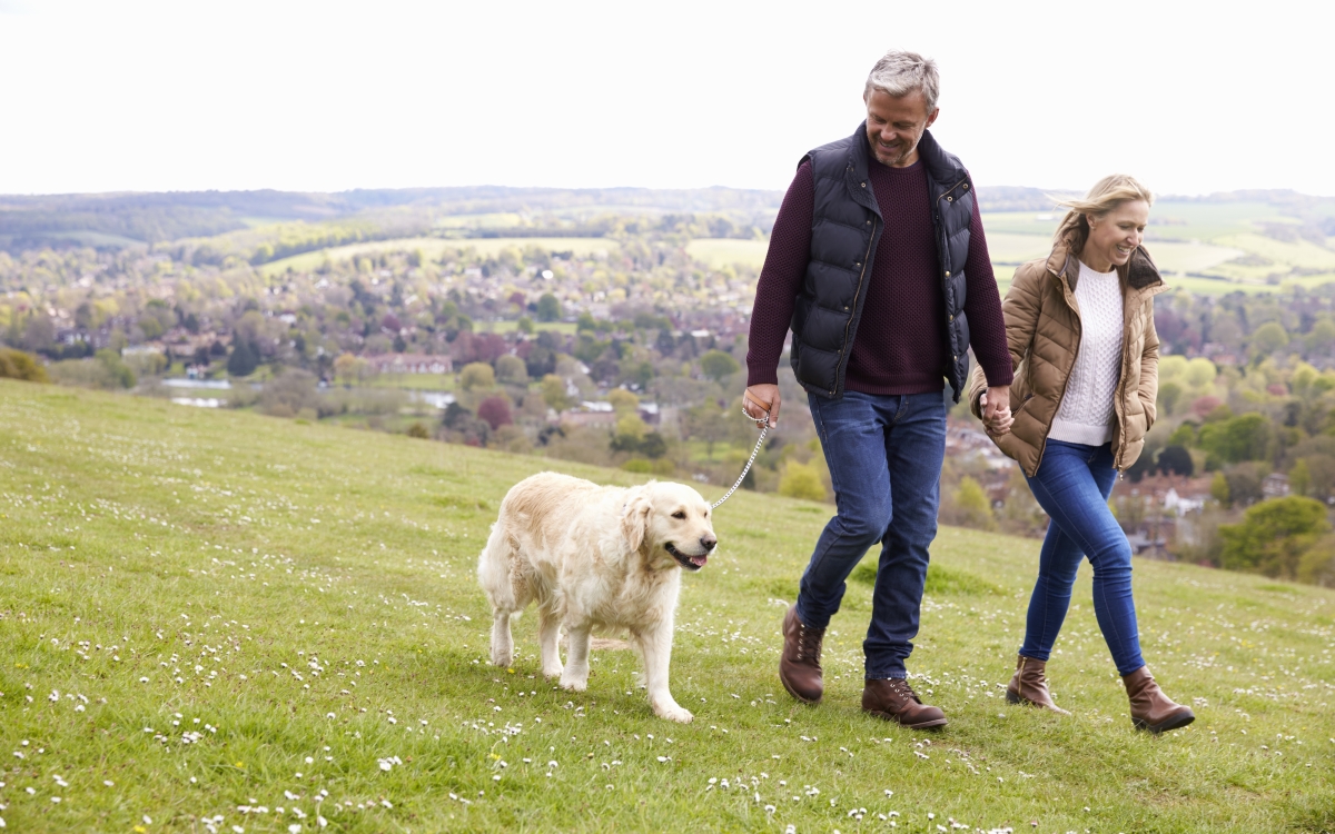 Älteres Paar geht mit ihrem Hund auf dem Land spazieren
