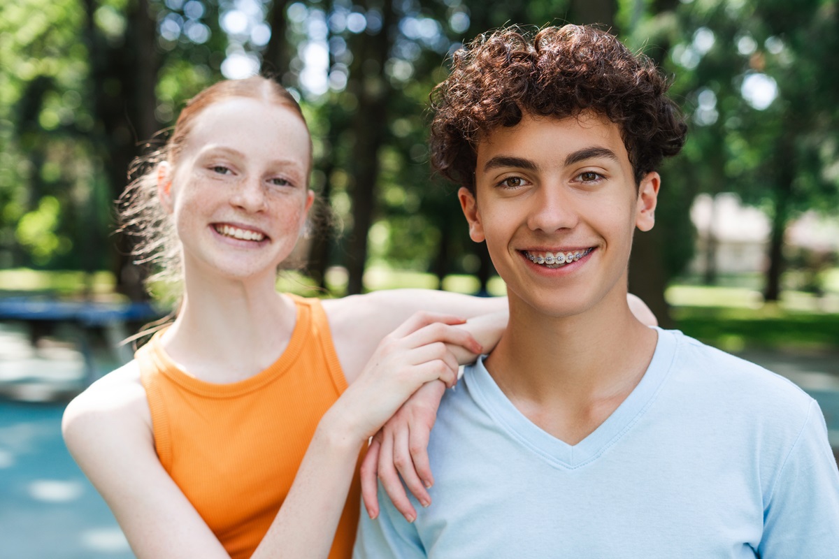 Gl&uuml;ckliche Teenager-Freunde im Park, der Junge tr&auml;gt eine Zahnspange.