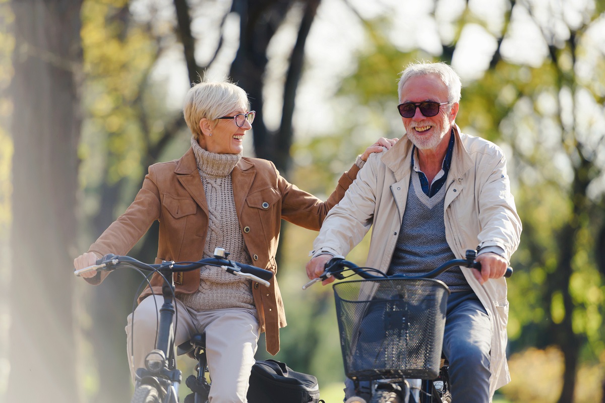 Seniorin und Senior fahren zusammen mit dem Fahrrad durch einen schönen Park