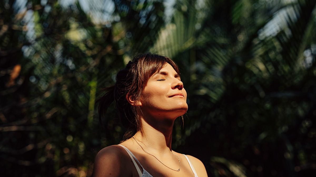Schöne glückliche Frau genießt das Sonnenlicht im Gesicht