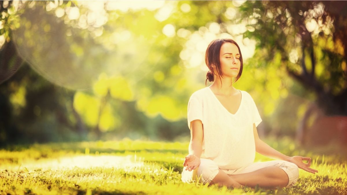 BKK-VBU Versicherten-Newsletter: Bildes einer Frau auf einer Wieser die dort meditiert. 