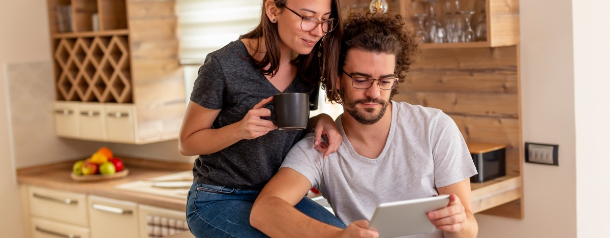 Eine Frau und ein Mann lesen zusammen etwas auf einem Tablet-Computer in der K&uuml;che