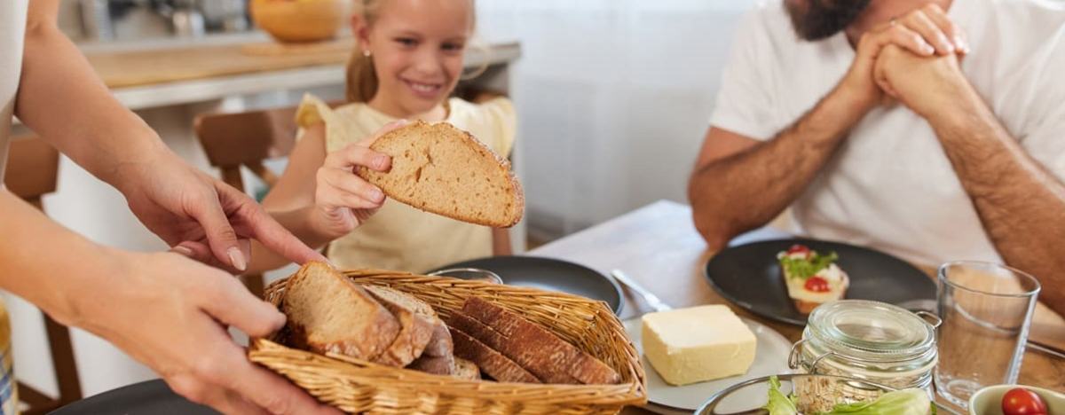 Die Familie genie&szlig;t zu Hause eine gemeinsame Mahlzeit mit frischem Brot, Salat und Butter.