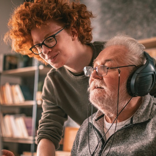 Gro&szlig;vater und Enkel sitzen zu Hause am Tisch und benutzen den Computer