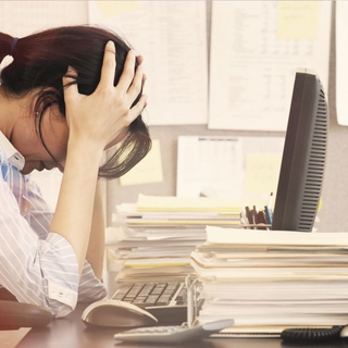 Frau im B&uuml;ro schl&auml;gt vor lauter Stress die Arme &uuml;ber dem Kopf zusammen