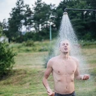 Ein Mann duscht kalt in der Natur.