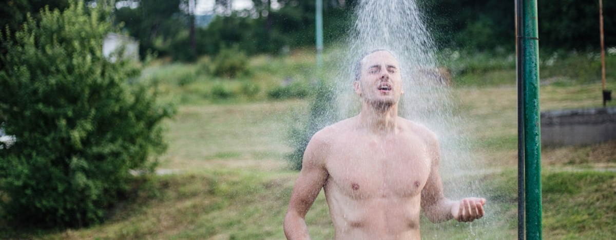 Ein Mann duscht kalt in der Natur.