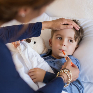 Eine Mutter misst oral Fieber bei ihrem Sohn.