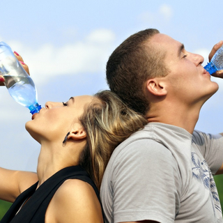 Frau und Mann k&uuml;hlen sich mit Wasser trinken nach dem Sport ab
