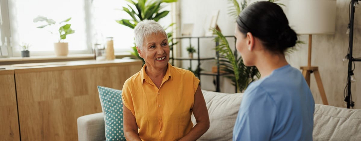 Seniorin unterh&auml;lt sich nett mit einer Krankenschwester zu Hause.
