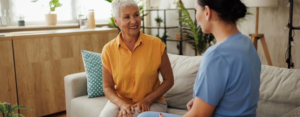 Seniorin unterh&auml;lt sich nett mit einer Krankenschwester zu Hause.