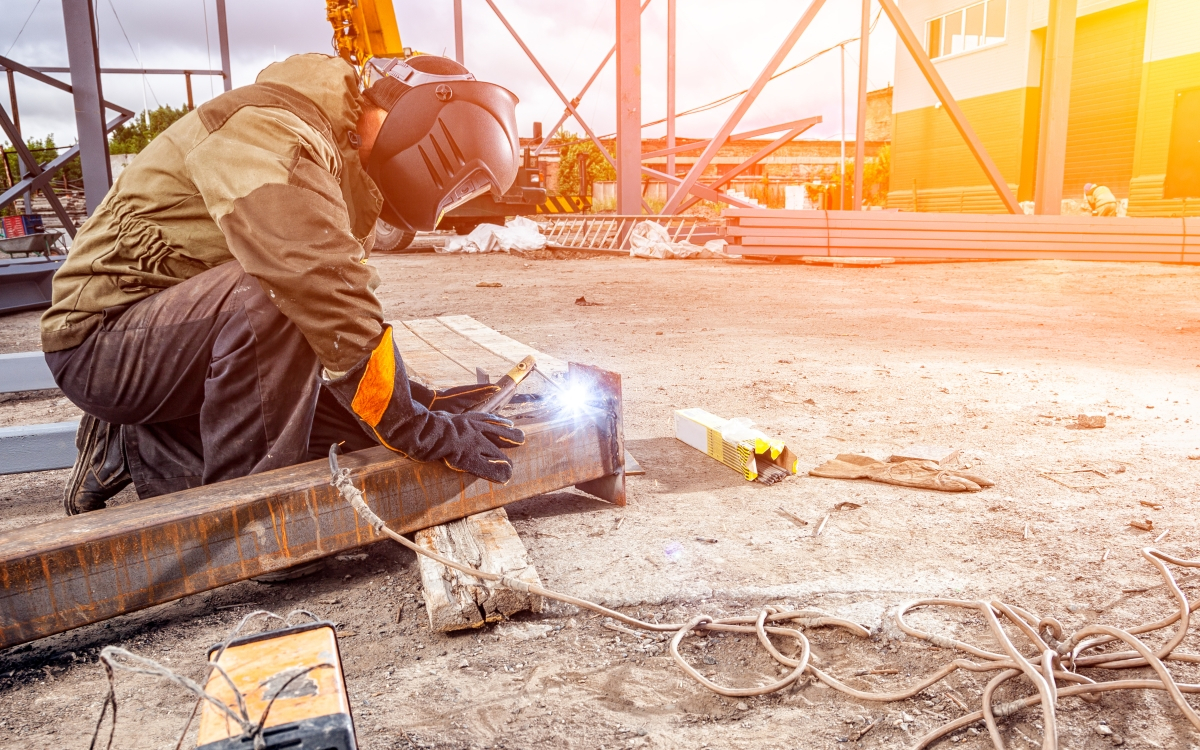 Arbeiter schwei&szlig;t in einer Werkshalle an einem Bauteil