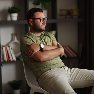 Overthinking: Ein Mann sitzt auf einem Stuhl und schaut nachdenklich aus dem Fenster.