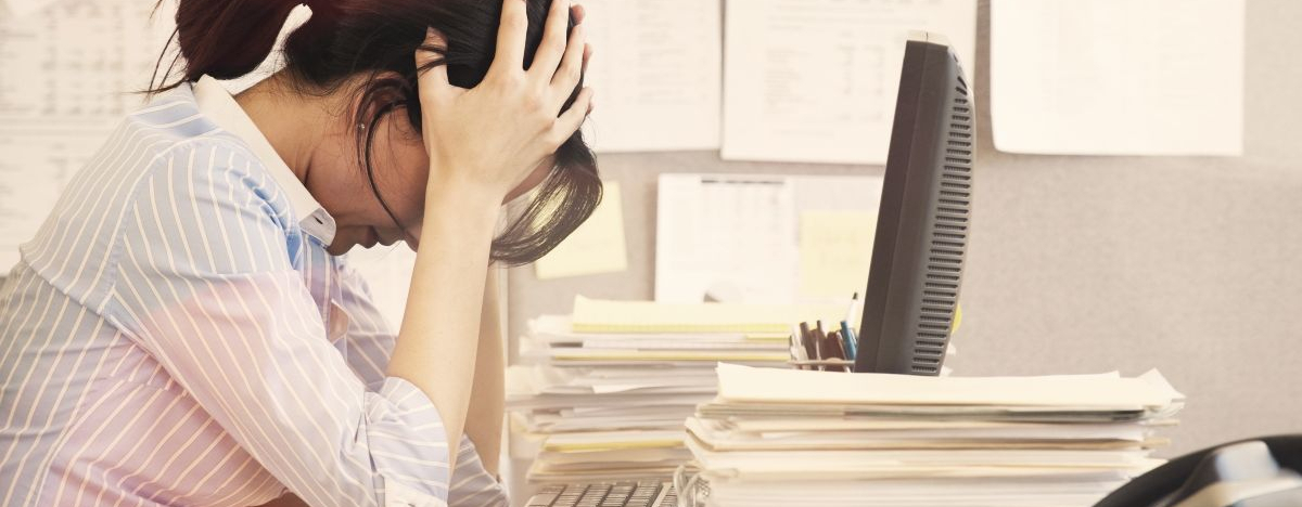 Frau im B&uuml;ro schl&auml;gt vor lauter Stress die Arme &uuml;ber dem Kopf zusammen