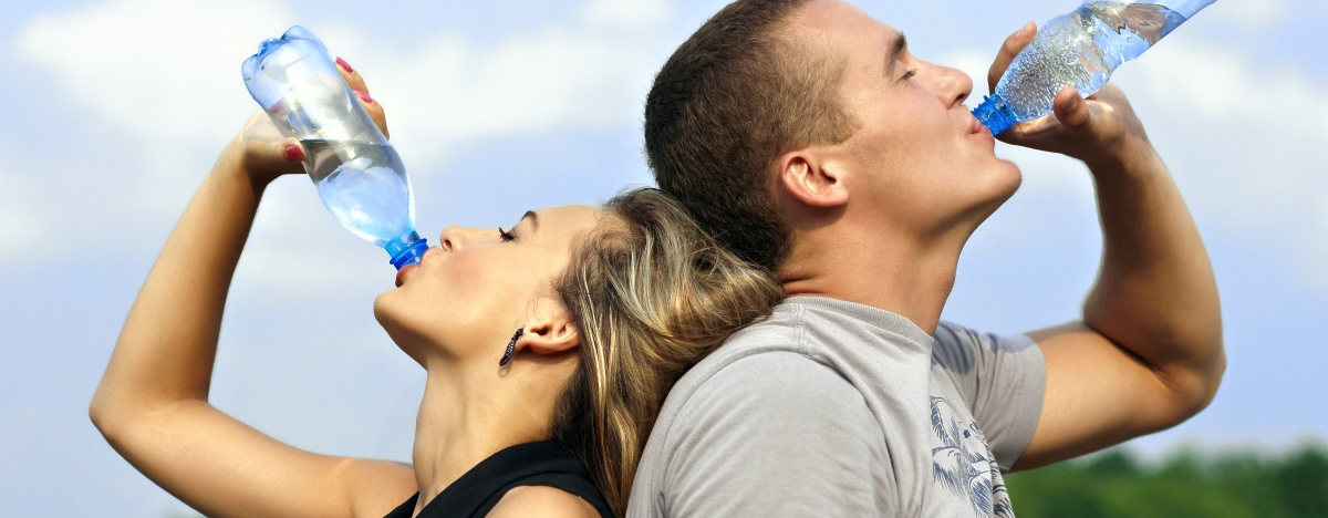Frau und Mann k&uuml;hlen sich mit Wasser trinken nach dem Sport ab