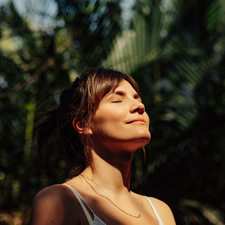 Sch&ouml;ne gl&uuml;ckliche Frau genie&szlig;t das Sonnenlicht im Gesicht