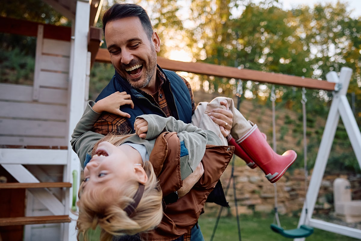 Fr&ouml;hlicher Vater und Tochter haben Spa&szlig; auf dem Spielplatz am Herbsttag.