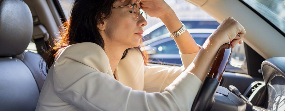 Eine gestresste Frau sitzt im Auto.