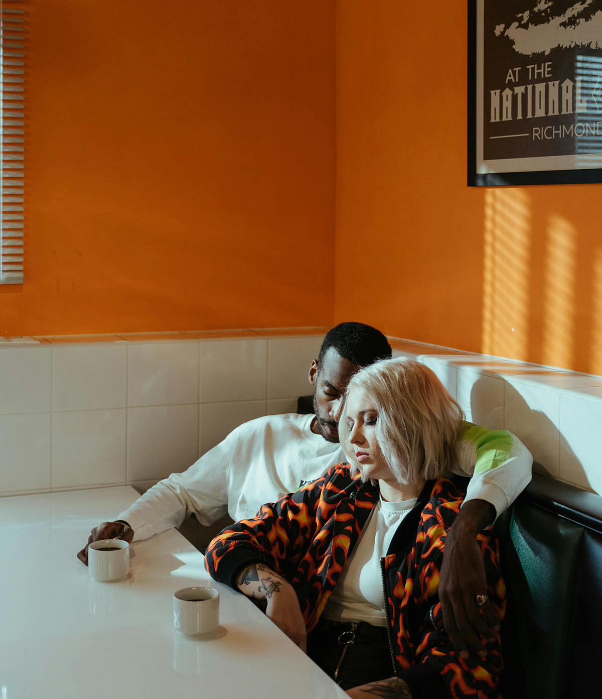 Zwei m&uuml;de Personen sitzen am Tisch, vor ihnen jeweils eine Tasse Kaffee