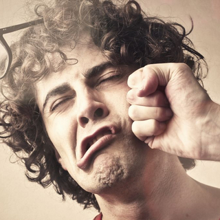 Mann bekommt mit der Faust einen Schlag ins Gesicht