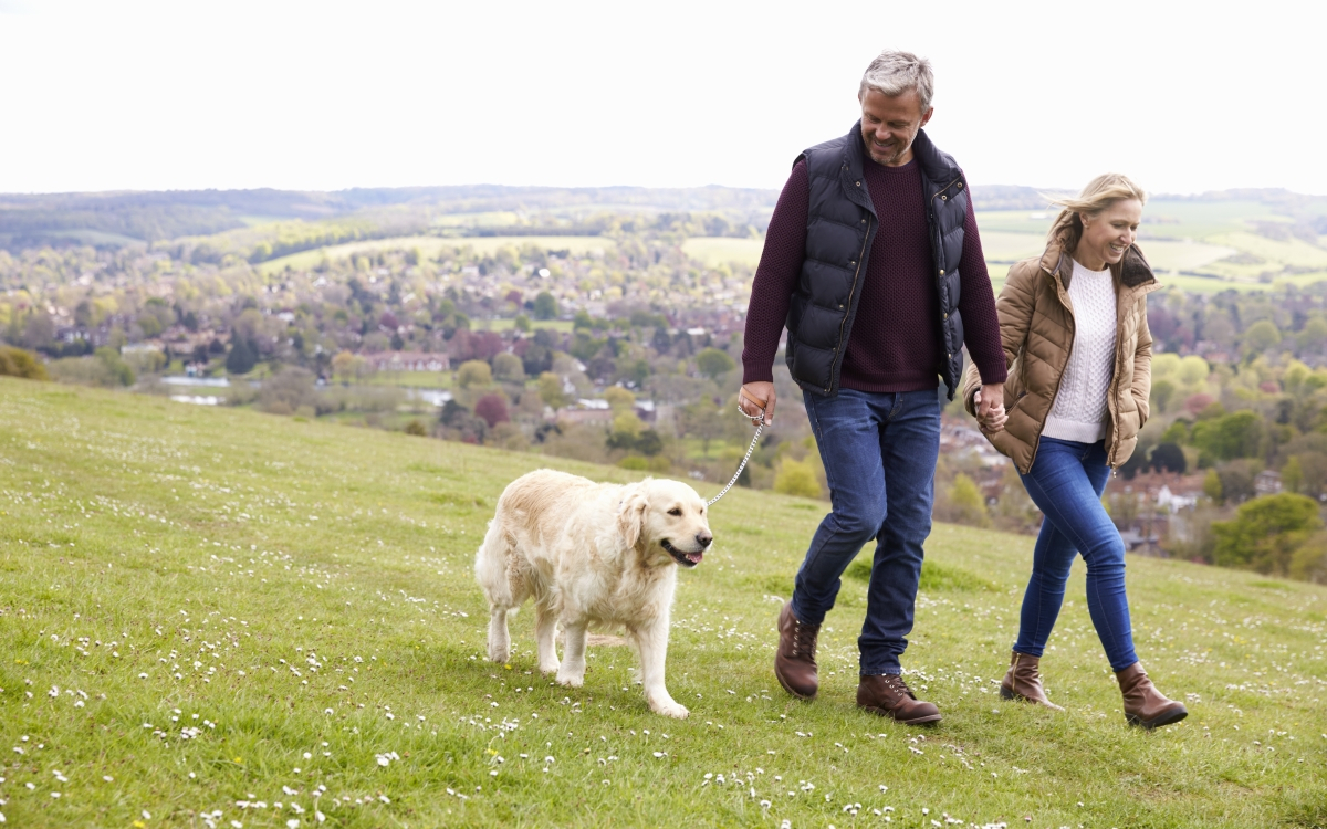 &Auml;lteres Paar geht mit ihrem Hund auf dem Land spazieren