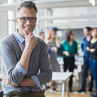 Ein erfahrener Teamleiter l&auml;chelt in die Kamera.