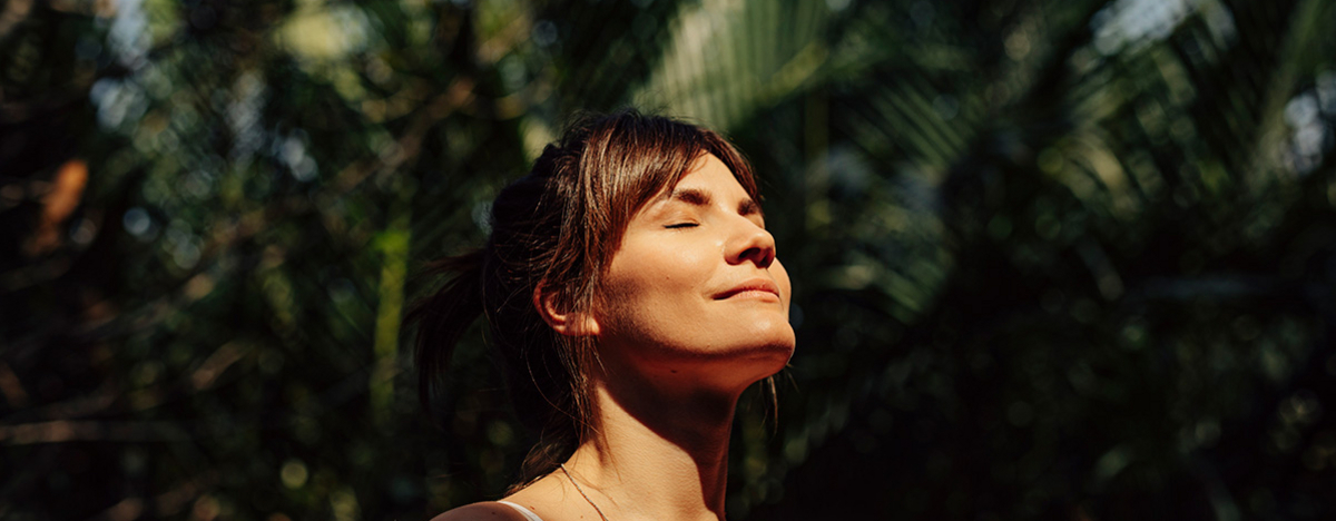 Sch&ouml;ne gl&uuml;ckliche Frau genie&szlig;t das Sonnenlicht im Gesicht
