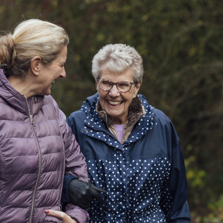 Frau geht mit ihrer Mutter spazieren und lacht