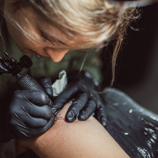 Frau t&auml;towiert eine Person auf dem Unterarm