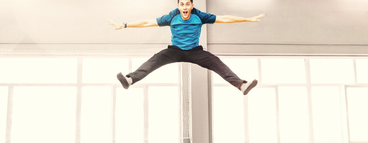 Mann springt in einer Halle auf einem gro&szlig;en Trampolin.