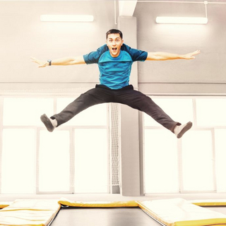 Mann springt in einer Halle auf einem gro&szlig;en Trampolin.