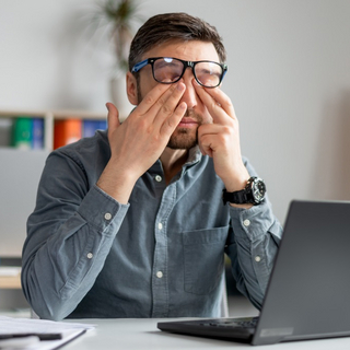 Mann im B&uuml;ro reibt sich die Augen vor M&uuml;digkeit