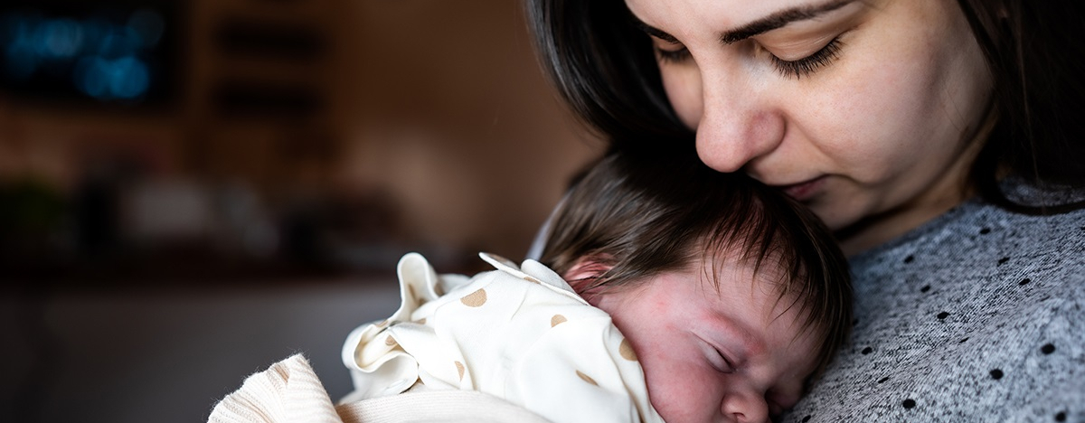 Mutter h&auml;lt neugeborenes Baby auf dem Arm