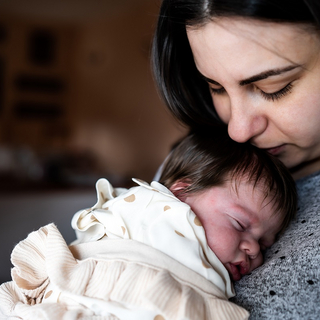 Mutter h&auml;lt neugeborenes Baby auf dem Arm