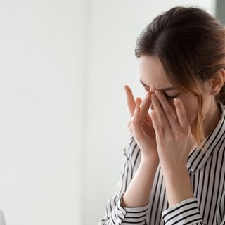Frau sitzt vor dem Laptop und reibt sich die m&uuml;den Augen