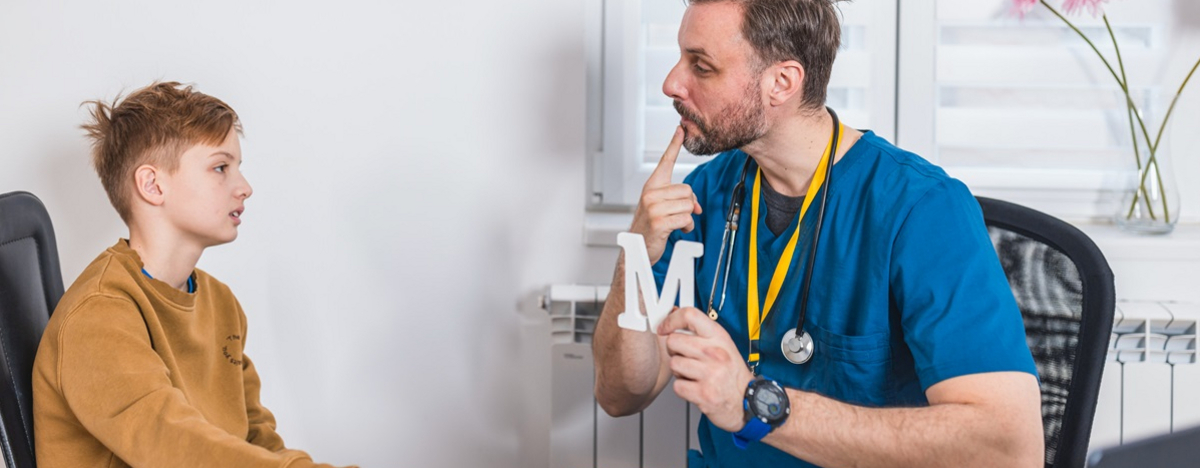 Eine Junge und ein Logop&auml;de machen Stimmtraining gegen Artikulationsst&ouml;erungen.