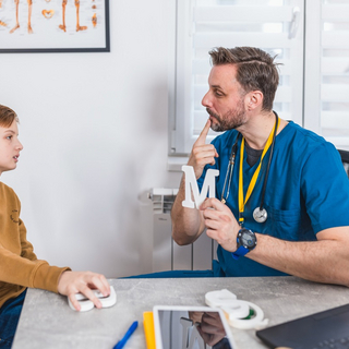 Eine Junge und ein Logop&auml;de machen Stimmtraining gegen Artikulationsst&ouml;erungen.