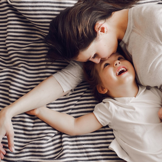 Ratgeber Meningokokken: Mutter liegt mit Kind auf dem Bett