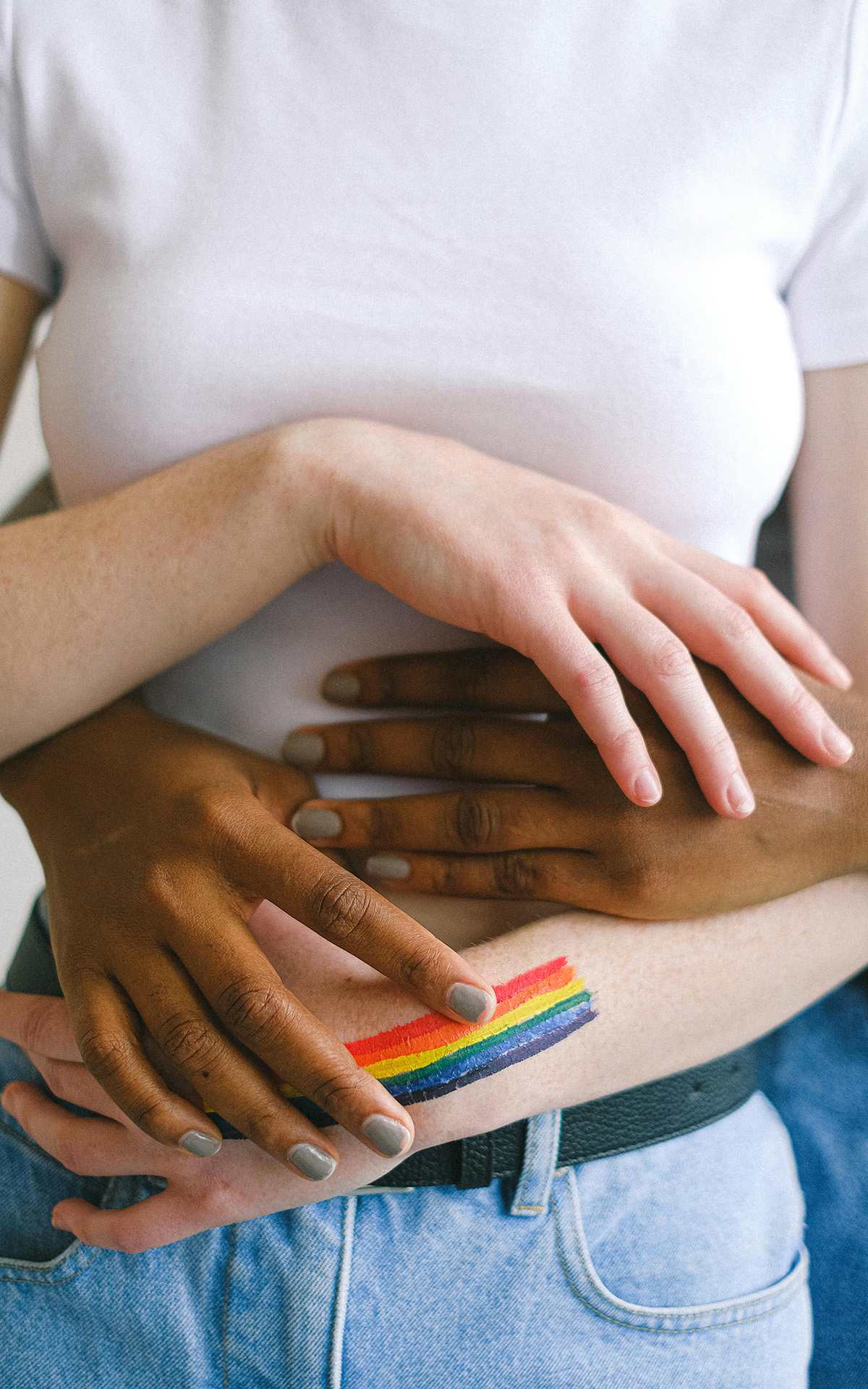 Ein gleichgeschlechtliches Paar umarmt sich, sie haben ein Regenbogen Tattoo am Arm