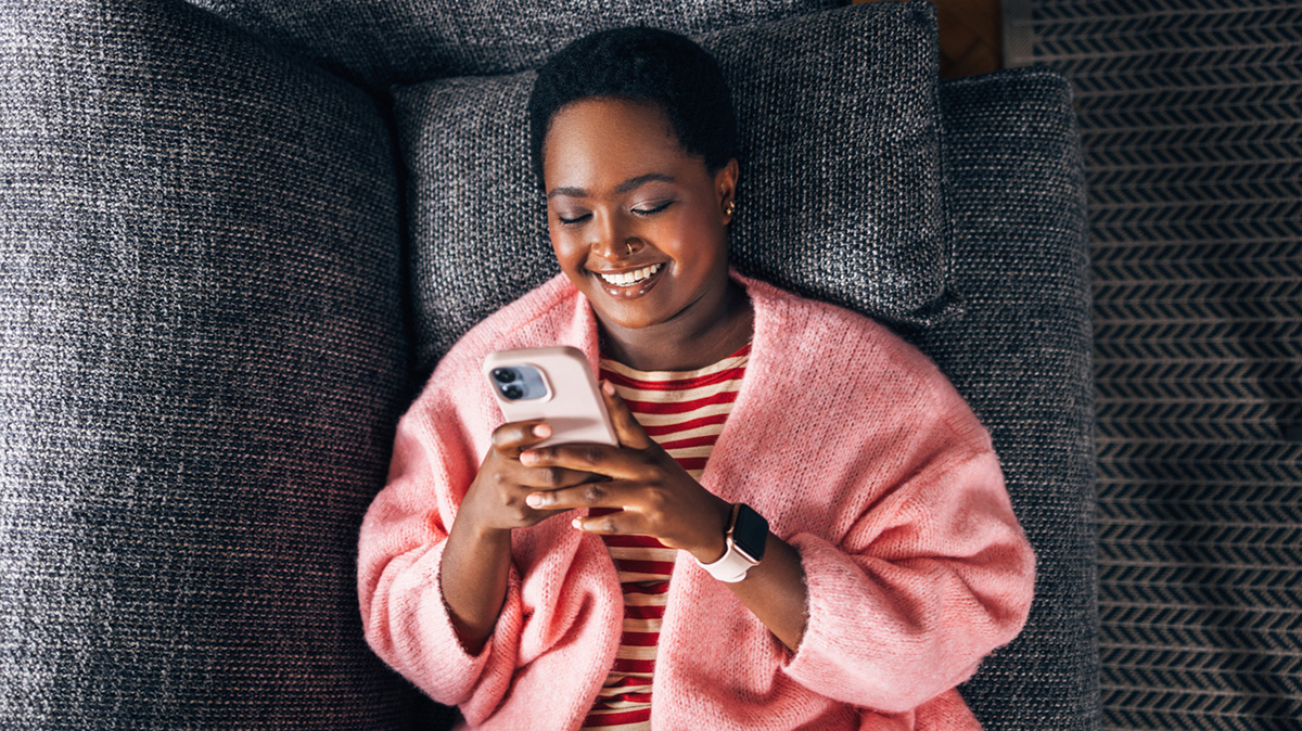 M&auml;dchen liegt auf Sofa und sieht auf ihr Handy