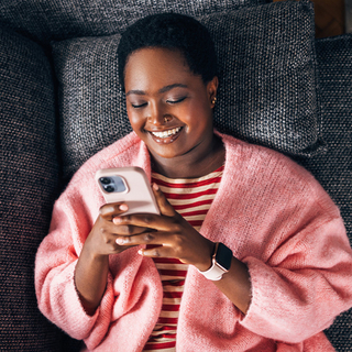 M&auml;dchen liegt auf Sofa und sieht auf ihr Handy