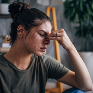 Frau ber&uuml;hrt die Stirn, w&auml;hrend sie sich unwohl f&uuml;hlt.