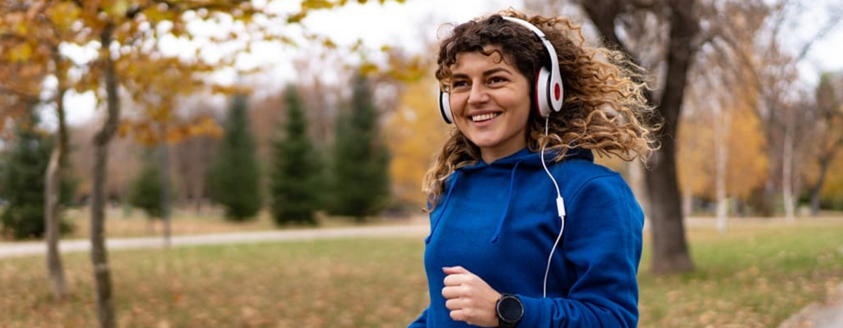 Eine junge Frau joggt im Herbst durch den Park.