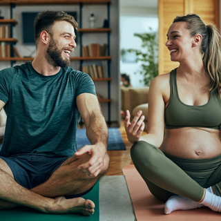 schwangere Frau macht zusammen mit ihrem Mann Yoga