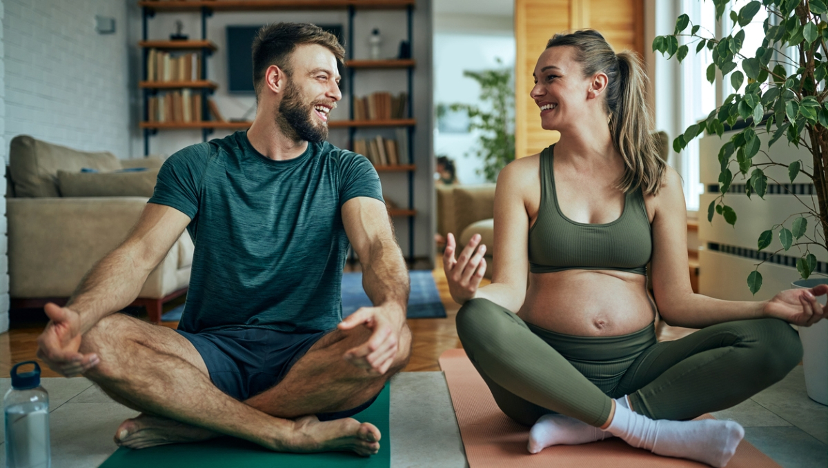 schwangere Frau macht zusammen mit ihrem Mann Yoga