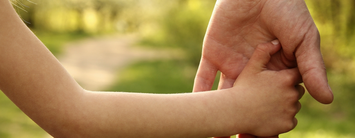 Eine Kinderhand h&auml;lt sich an einer Hand eines Erwachsenden fest.