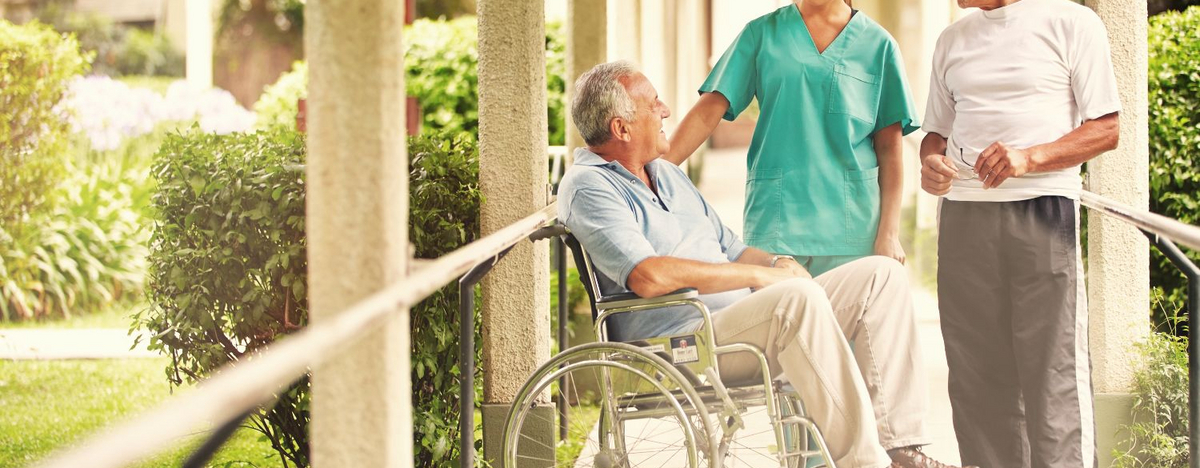 Pflegerin unterh&auml;lt sich mit Patienten im Garten.