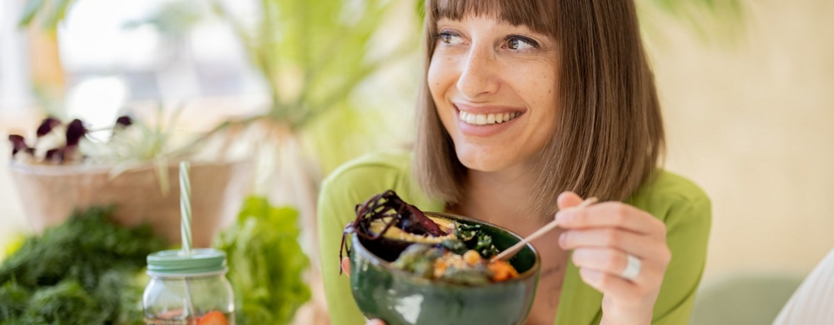 Entspannte Frau mit gesundem Essen im Zimmer mit Pflanzen