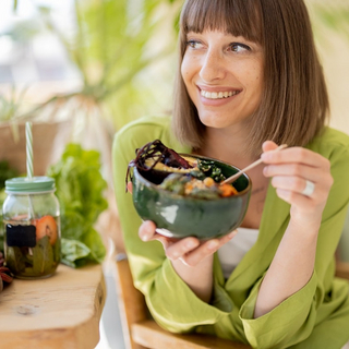 Entspannte Frau mit gesundem Essen im Zimmer mit Pflanzen