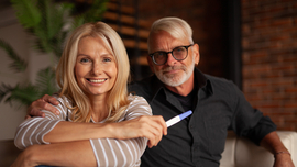 Gl&uuml;cklicher reifer Ehemann und Ehefrau mit Schwangerschaftstest
